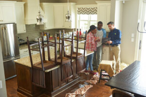 A ServiceMaster technician assessing kitchen water damage with homeowners, showing details on a tablet, in Lexington, KY.