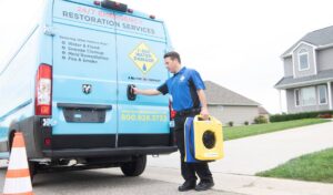 A technician carrying an air mover to a company van for 1-800 WATER DAMAGE of Oklahoma City, OK, ready for a water damage job.