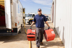 A TriForce Restoration technician carrying air movers for water damage drying in Moore, OK.