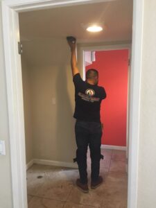 A technician from EZ Water Damage Restoration Services checking moisture levels on a ceiling with a meter in Chula Vista, CA.