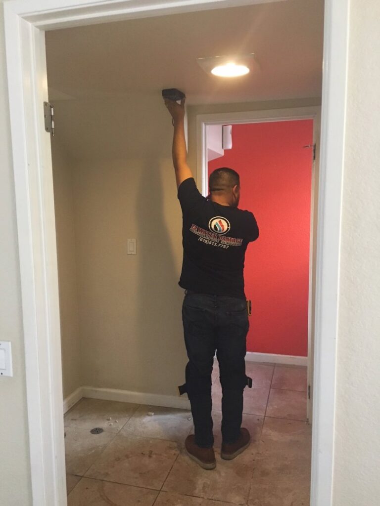 A technician from EZ Water Damage Restoration Services checking moisture levels on a ceiling with a meter in Chula Vista, CA.