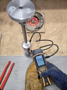A technician checking moisture levels in a subfloor with a SurveyMaster meter for Harbaugh Restoration in Vancouver, WA.