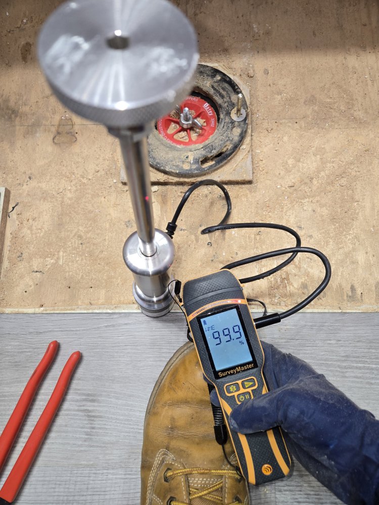 A technician checking moisture levels in a subfloor with a SurveyMaster meter for Harbaugh Restoration in Vancouver, WA.