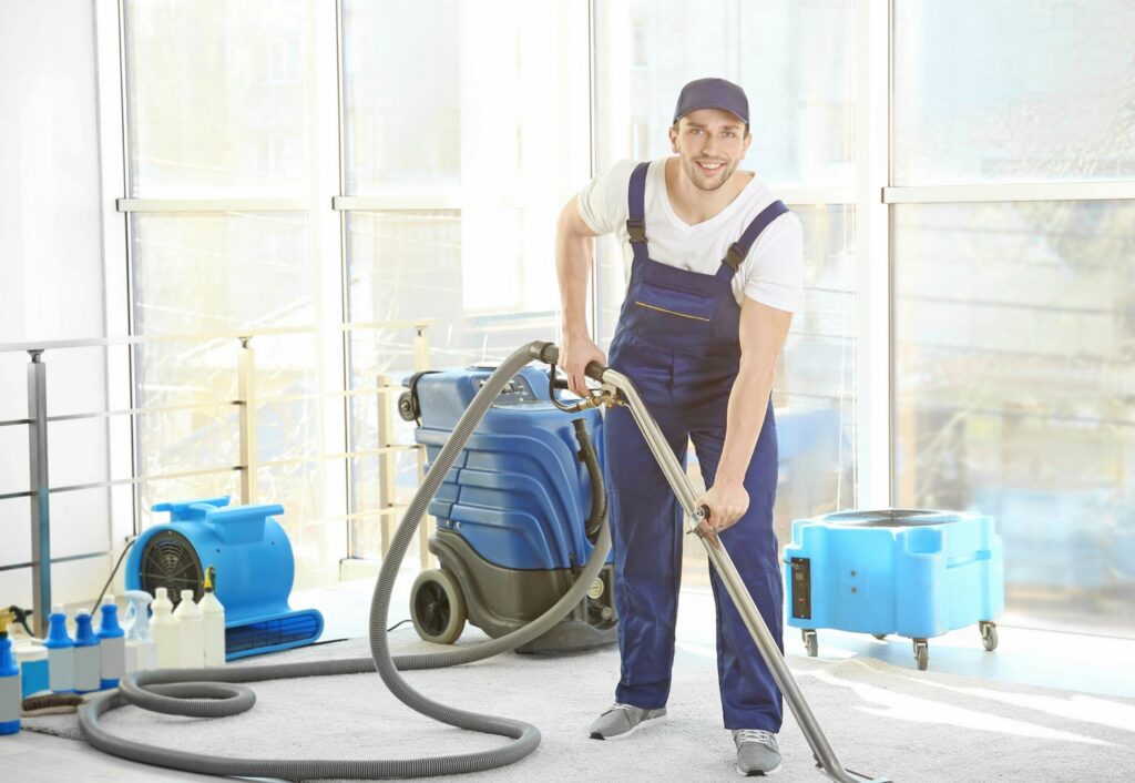 A water damage technician cleaning a carpet with a professional extractor and air movers at Water Damage Pro in Minneapolis, MN