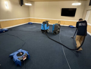 A technician cleaning a carpet with an extractor, surrounded by air movers during water damage restoration by KY Water Damage Restoration in Georgetown, KY.
