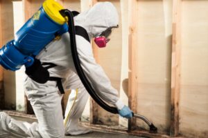 A technician in a hazmat suit cleaning mold from wooden studs, a service provided by 1-800 WATER DAMAGE of Oklahoma City, OK.