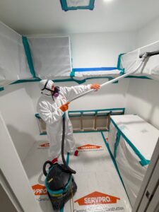 A Servpro of Sandy technician in a hazmat suit performing specialized cleaning and remediation in a contained room in Sandy, UT.