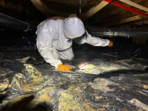 A Restorex technician in a hazmat suit inspecting a crawl space for water damage or mold in Petaluma, CA.