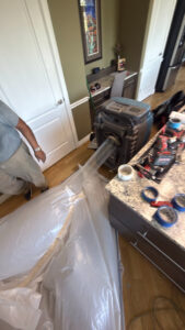 A technician setting up drying equipment and containment sheeting for water damage restoration in Syracuse, UT by Utah Disaster Specialists.