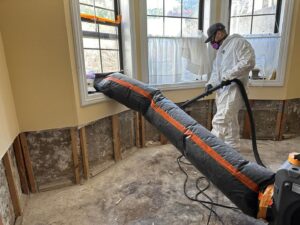 A Restorex technician in a hazmat suit drying a wall cavity after water damage in a home in Petaluma, CA.
