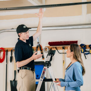 A Precision Garage Door Service of NC technician explaining a garage door repair to a customer in Morrisville, NC.