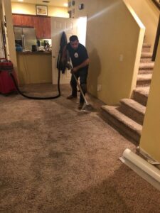 A technician from EZ Water Damage Restoration Services extracting water from a carpeted floor during restoration in Chula Vista, CA.