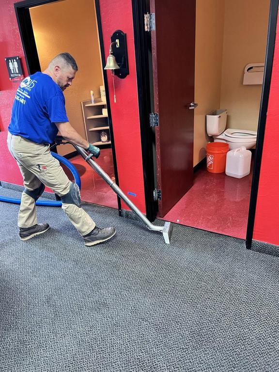 A technician from Lotus Restoration Services extracting water from a carpeted floor in Gilbert, AZ, during a water damage job.
