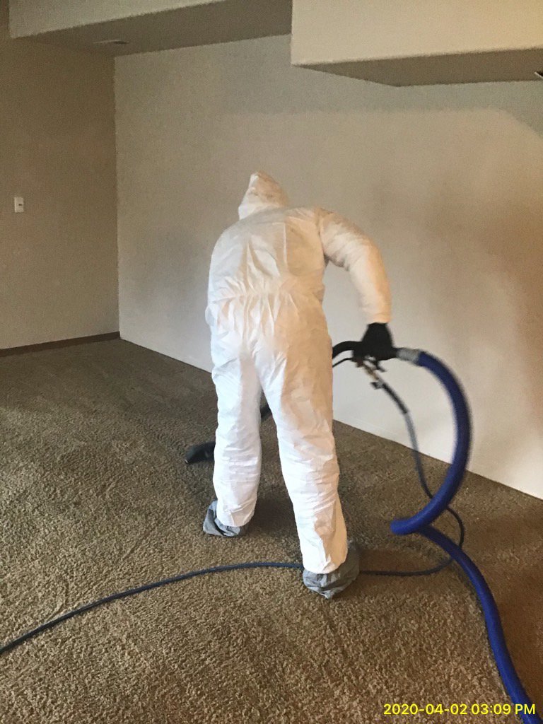 A technician in a protective suit performing water extraction from a carpeted floor for Rainbow International of Coeur D'alene in Post Falls, ID