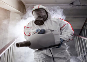 A technician in a hazmat suit performing fogging for disinfection or mold remediation after water damage by PROTECH Restoration & Cleaning in Philadelphia, PA.