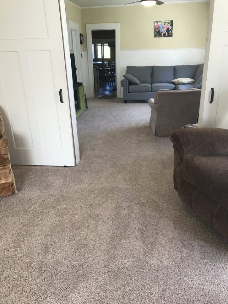 A technician from The Dry Guys using a moisture meter to inspect carpet for water damage in a home in Kenosha, WI.