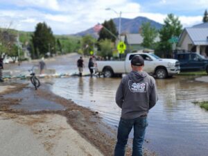 A 406 Disaster Response technician inspecting a flooded street after heavy rainfall in Billings, MT.