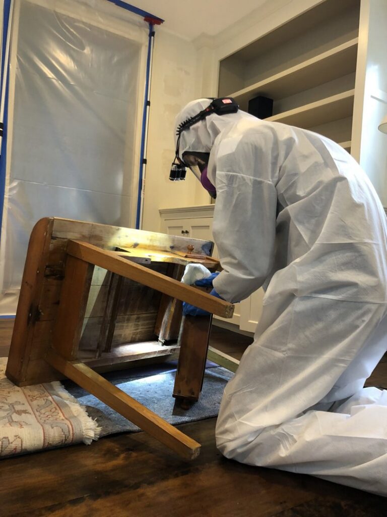 A Green Home Solutions technician in protective gear inspecting furniture for mold or water damage in Mount Airy, MD.
