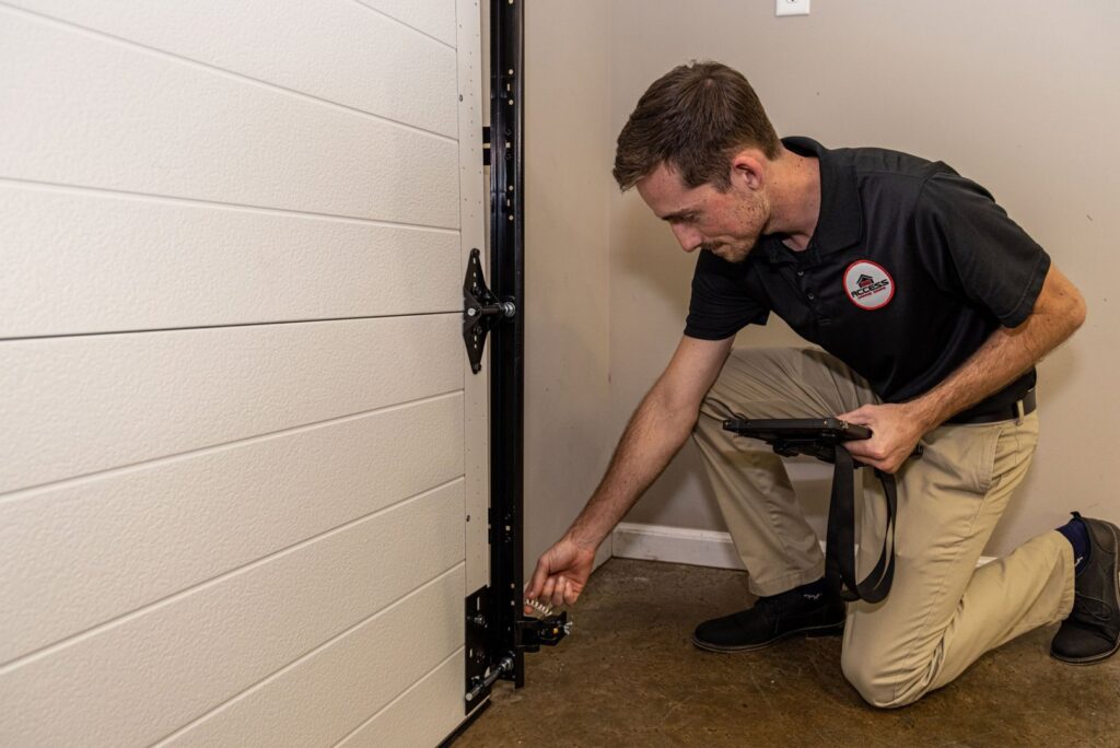 A technician from Access Garage Doors of Treasure Valley inspecting garage door hardware and rollers in Meridian, ID.