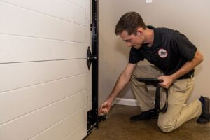 A technician from Access Garage Doors of Treasure Valley inspecting garage door hardware and rollers in Meridian, ID.