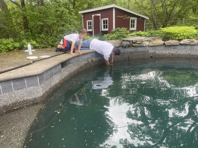 A technician inspecting the edge of a swimming pool for potential leaks or damage at South Shore Leak Solutions in Quincy, MA
