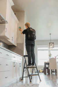 A technician inspecting a kitchen wall for hidden moisture with specialized equipment for APEX Restoration in Mililani, HI