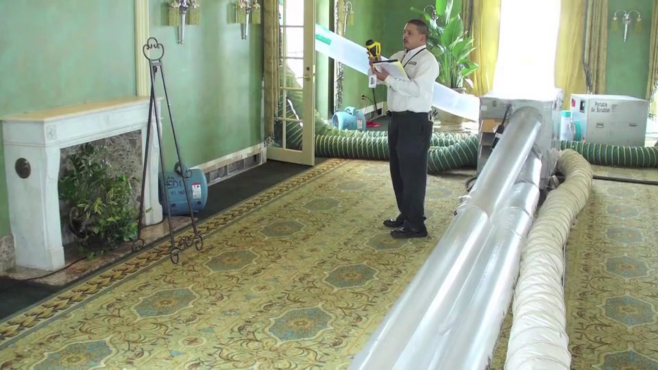 A COIT Cleaning and Restoration technician inspecting a room with large drying tubes and air movers for water damage in Indianapolis, IN
