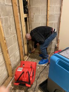 A technician inspecting a wall cavity for water damage with drying equipment nearby at Ungerman, Inc. in Plymouth, MN