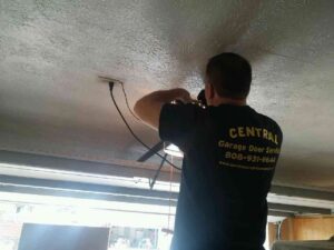 A Central Garage Door Service technician installing or repairing a garage door opener on the ceiling in Kapolei, HI.