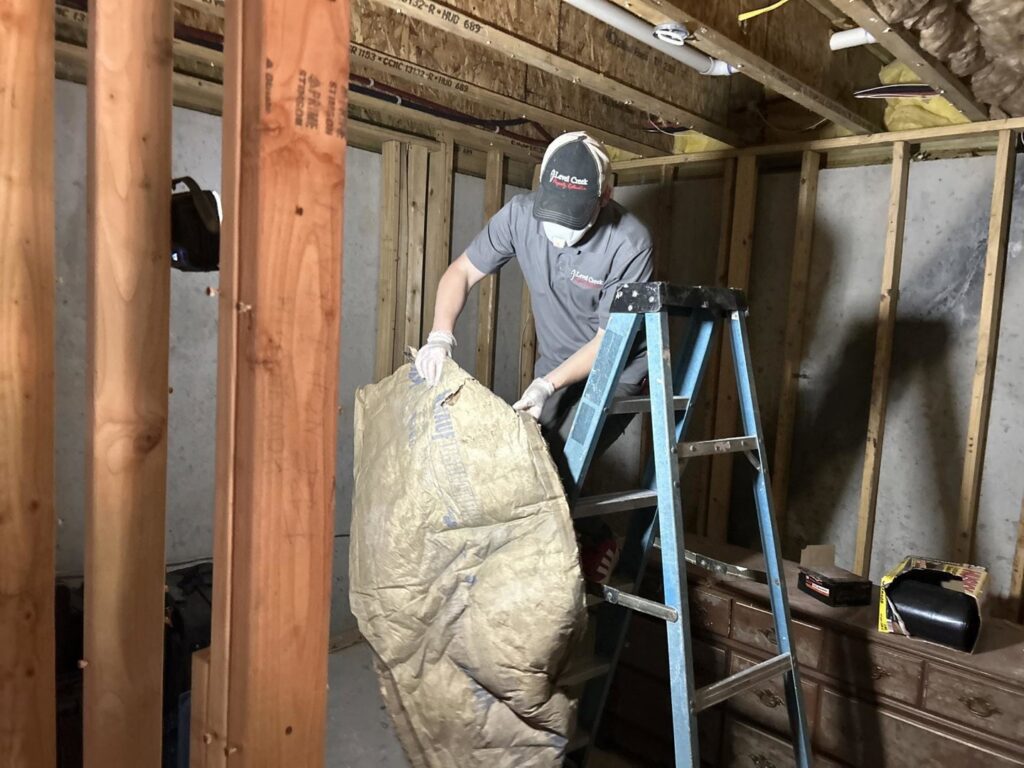 A technician from Level Creek Property Restoration installing insulation in a basement during a property restoration project in Buford, GA.