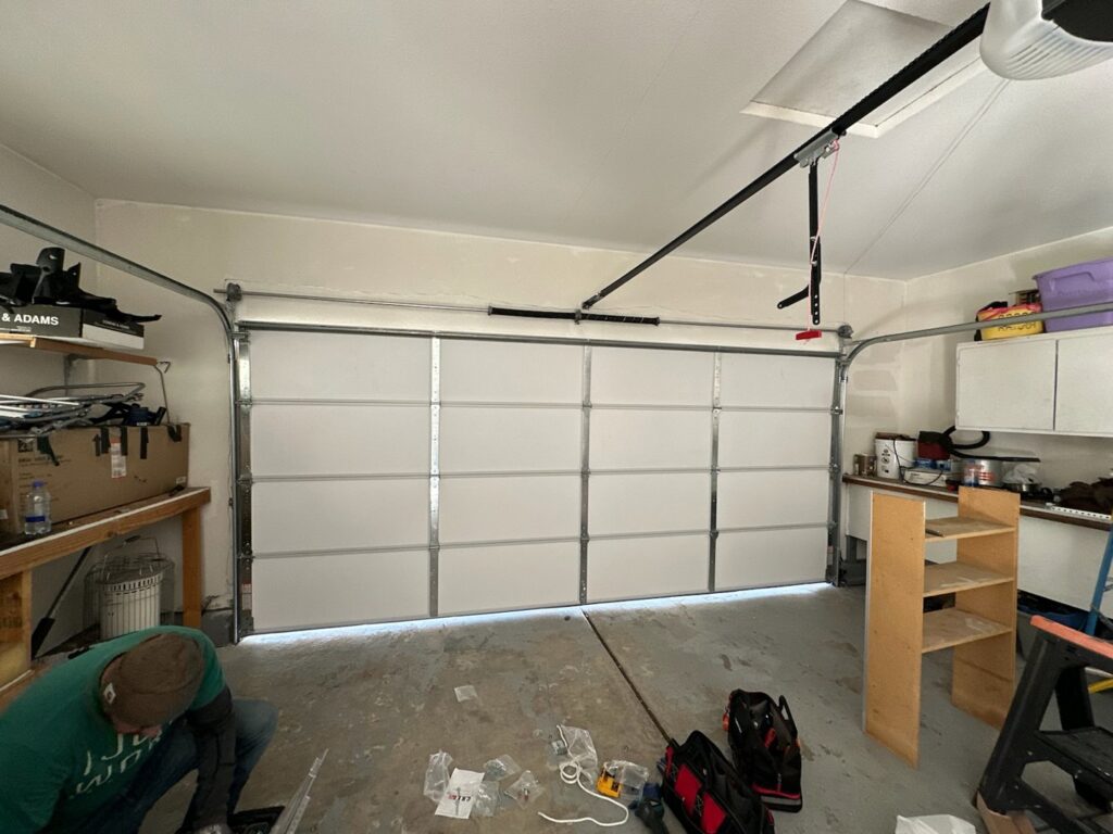 A technician installing a new white garage door inside a residential garage for 775 Overhead Doors in Carson City, NV.