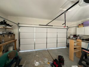 A technician installing a new white garage door inside a residential garage for 775 Overhead Doors in Carson City, NV.
