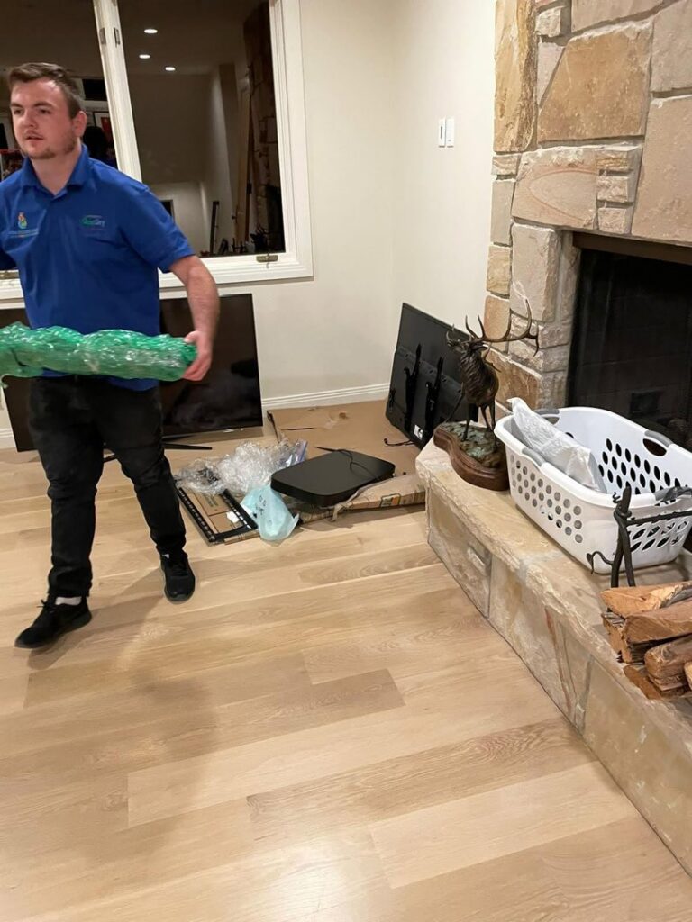 A technician from Utah Disaster Team moving wrapped contents during a water damage restoration project in Layton, UT.