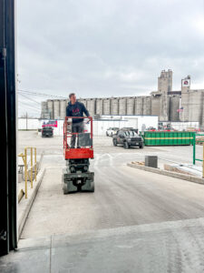 A technician on a scissor lift performing garage door work for Over The Top Garage in Albuquerque, NM.