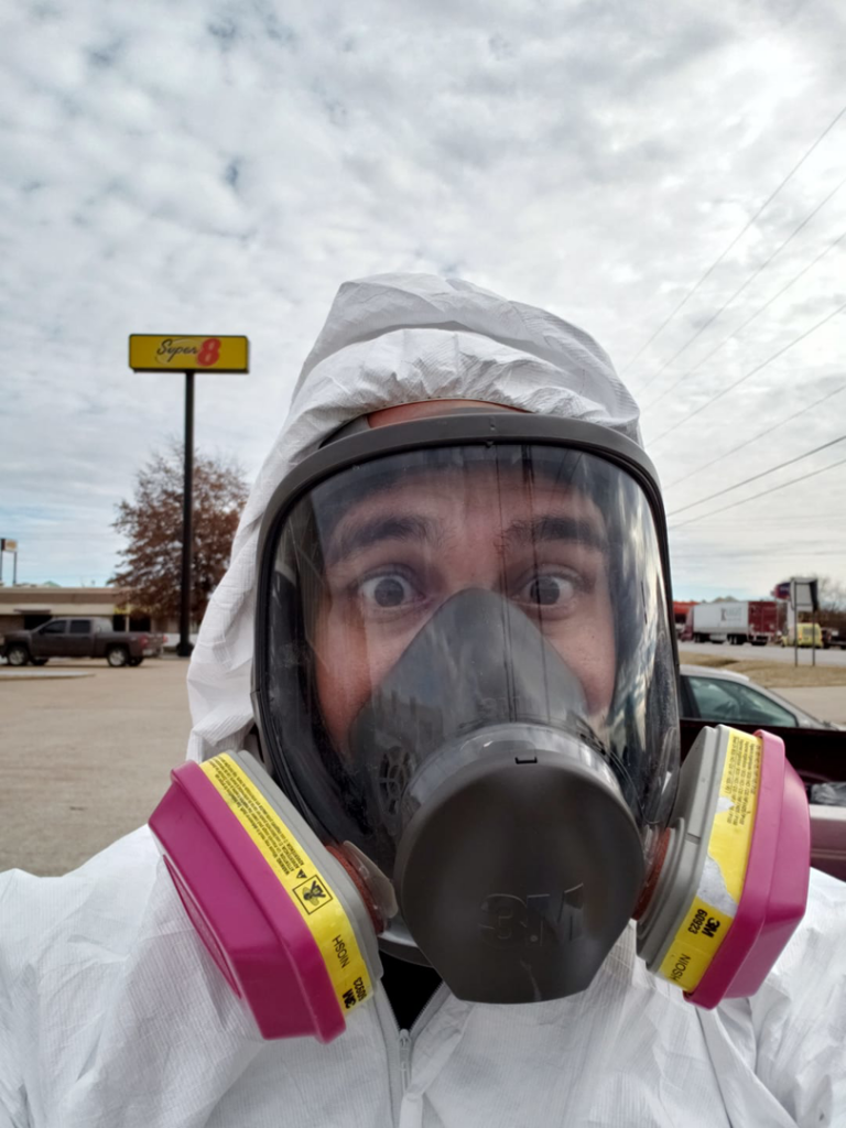 A technician wearing full PPE, including a respirator, for water damage or mold remediation at Natural State Restoration in Fayetteville, AR.