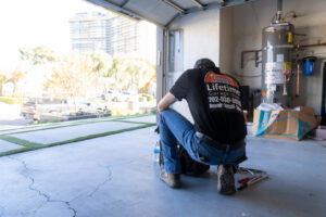 A Lifetime Garage Door technician kneeling with tools inside a garage, preparing for service in Las Vegas, NV.