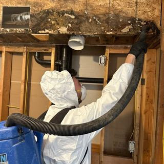 A technician in a hazmat suit performing remediation work on water-damaged and possibly moldy structural elements for Rainbow International of Coeur D'alene in Post Falls, ID