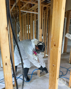 A technician in a hazmat suit performing water damage remediation in a framed room for United Water Restoration Group of Omaha, NE.