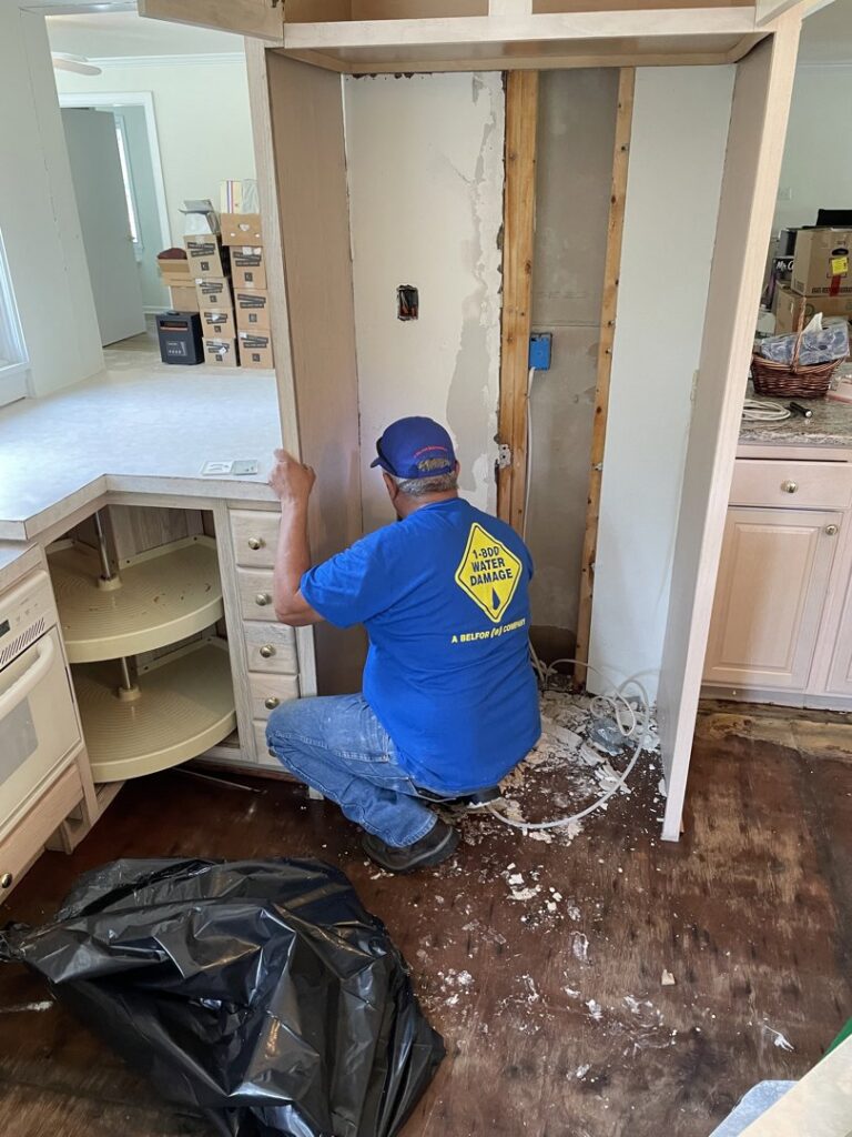 A technician from 1-800 Water Damage of Harrisburg, PA removing damaged kitchen cabinets during water damage remediation in York, PA.