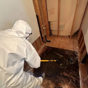 A technician in a protective suit removing water-damaged subfloor material during remediation by Rainbow International of Coeur D'alene in Post Falls, ID