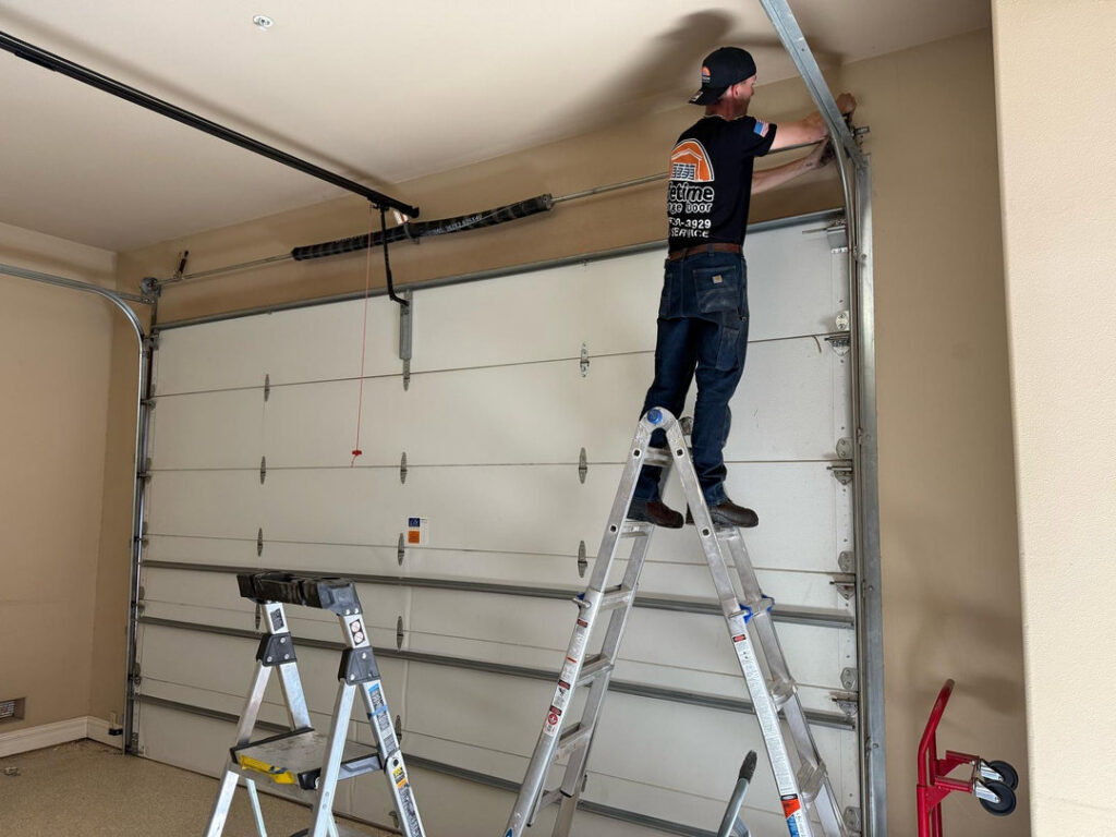A technician from Lifetime Garage Door on a ladder repairing a garage door mechanism in Las Vegas, NV.