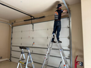 A technician from Lifetime Garage Door on a ladder repairing a garage door mechanism in Las Vegas, NV.