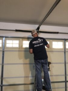 A ProLift Garage Doors of Canyon County technician on a ladder repairing garage door springs and hardware in Nampa, ID.