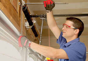 A technician wearing safety glasses and gloves repairing garage door springs for Sawtooth Garage Doors in Boise, ID.