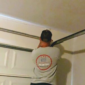 A technician from Ultimate Garage Doors LLC repairing a garage door opener mechanism in Olive Branch, MS.