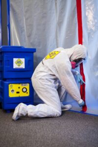 A technician in a hazmat suit sealing a containment area during mold remediation by 1-800 WATER DAMAGE of Oklahoma City, OK.