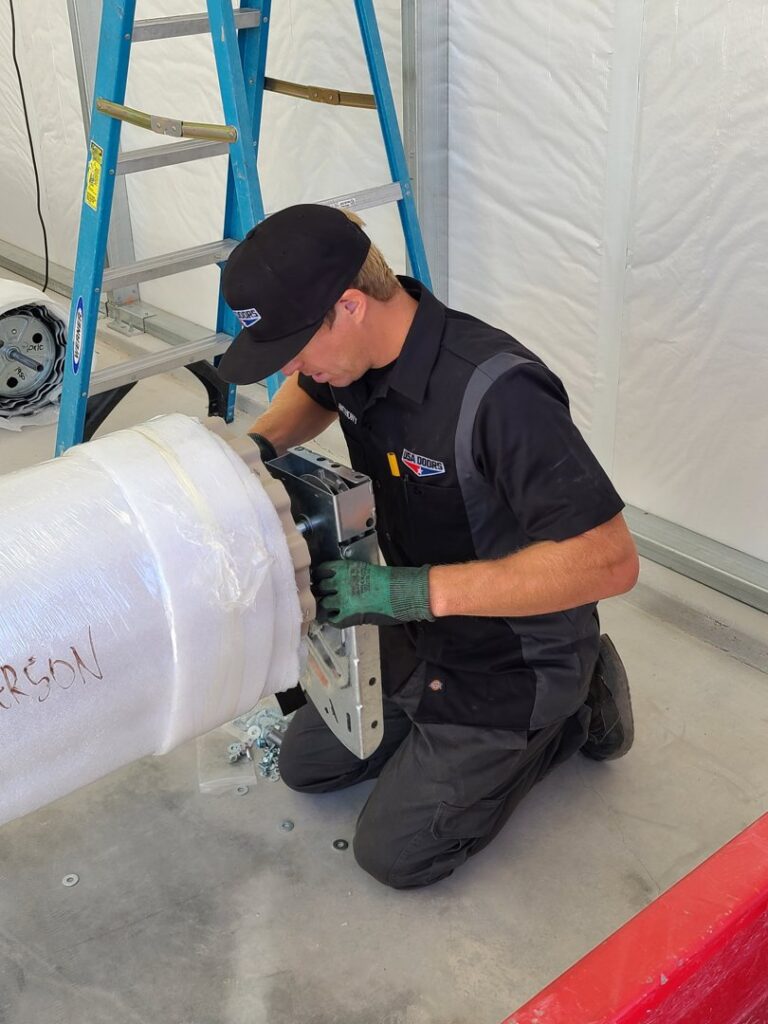 A technician from USA Doors servicing a rolling garage door mechanism in Doral, FL.