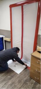 A technician setting up a plastic containment barrier for remediation work by SO-CO Water Damage in Pueblo, CO.
