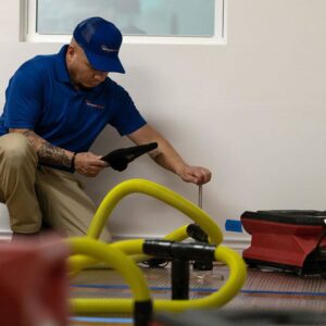 A technician setting up or checking a floor drying system for water damage restoration by AdvantaClean of Cabarrus and Rowan Counties in Concord, NC.