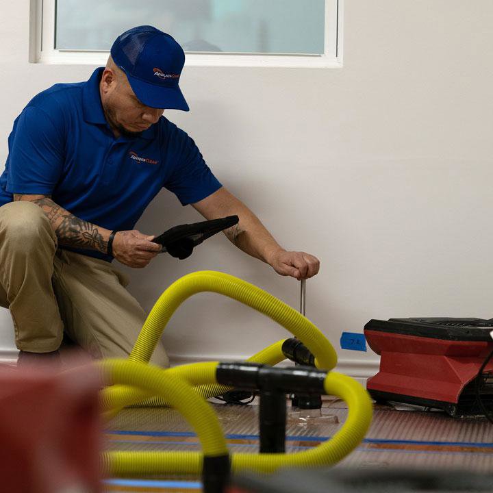 A technician setting up or checking a floor drying system for water damage restoration by AdvantaClean of Cabarrus and Rowan Counties in Concord, NC.